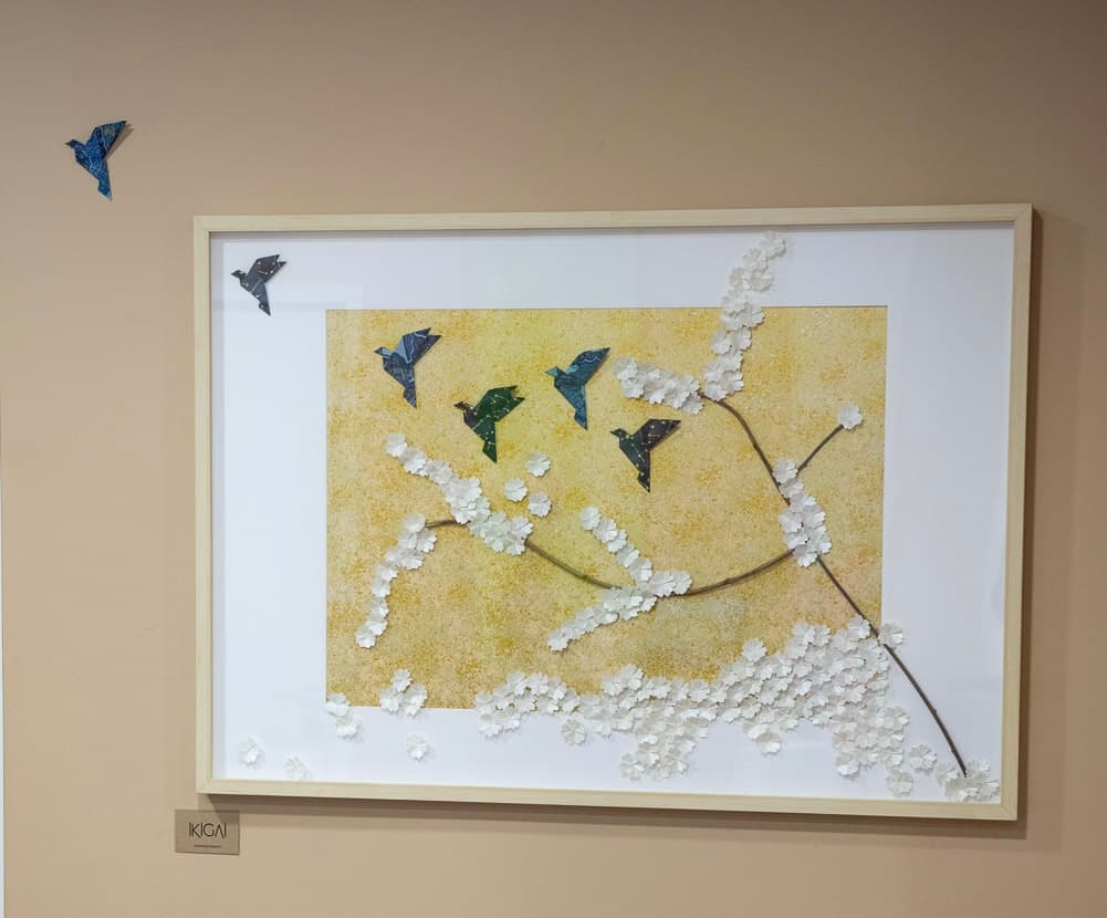 Cadre mural avec oiseaux en origami washi bleu et nuée de fleurs en papier blanc.