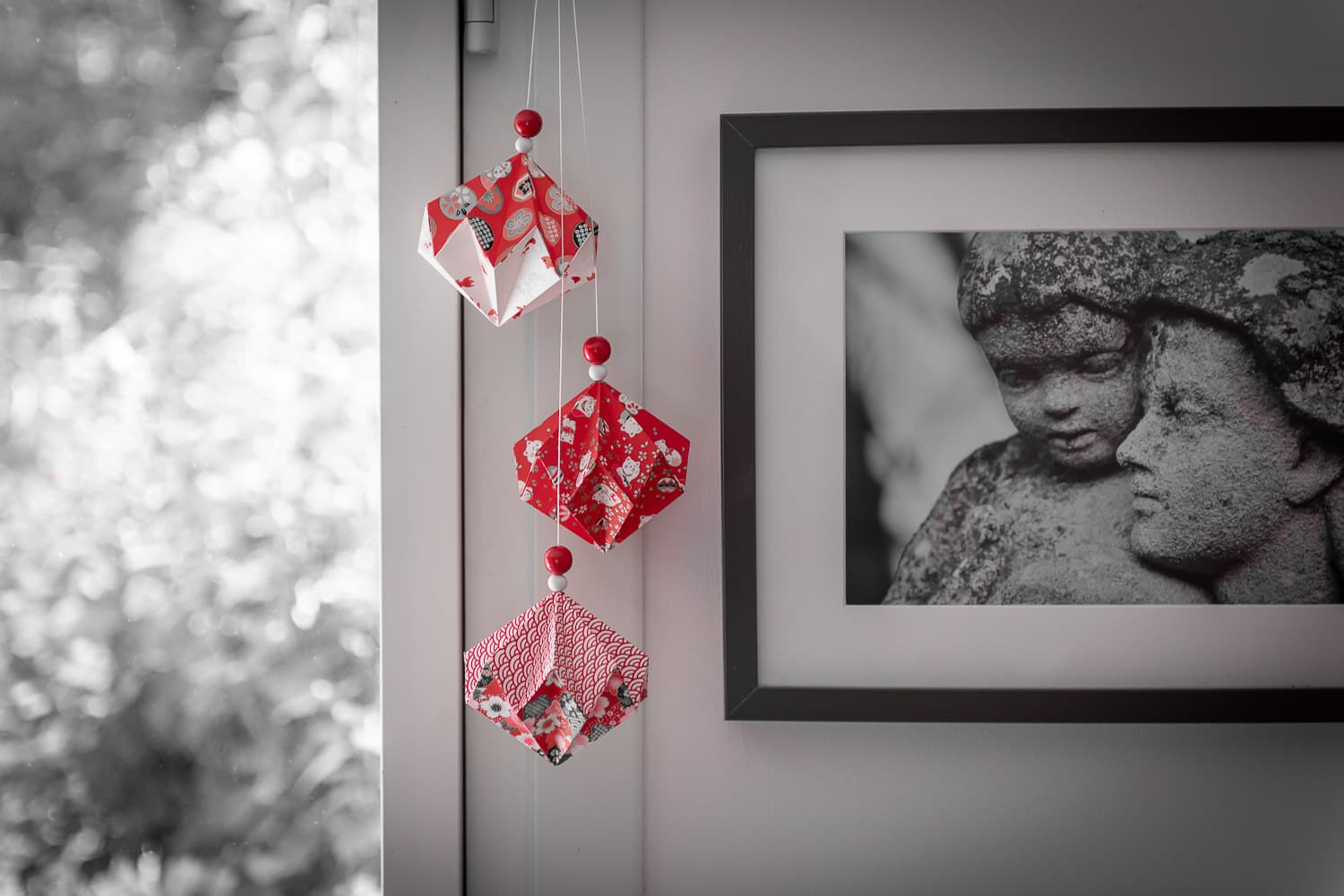 Pierres précieuses en origami washi rouge, suspendues près d'un cadre photo.