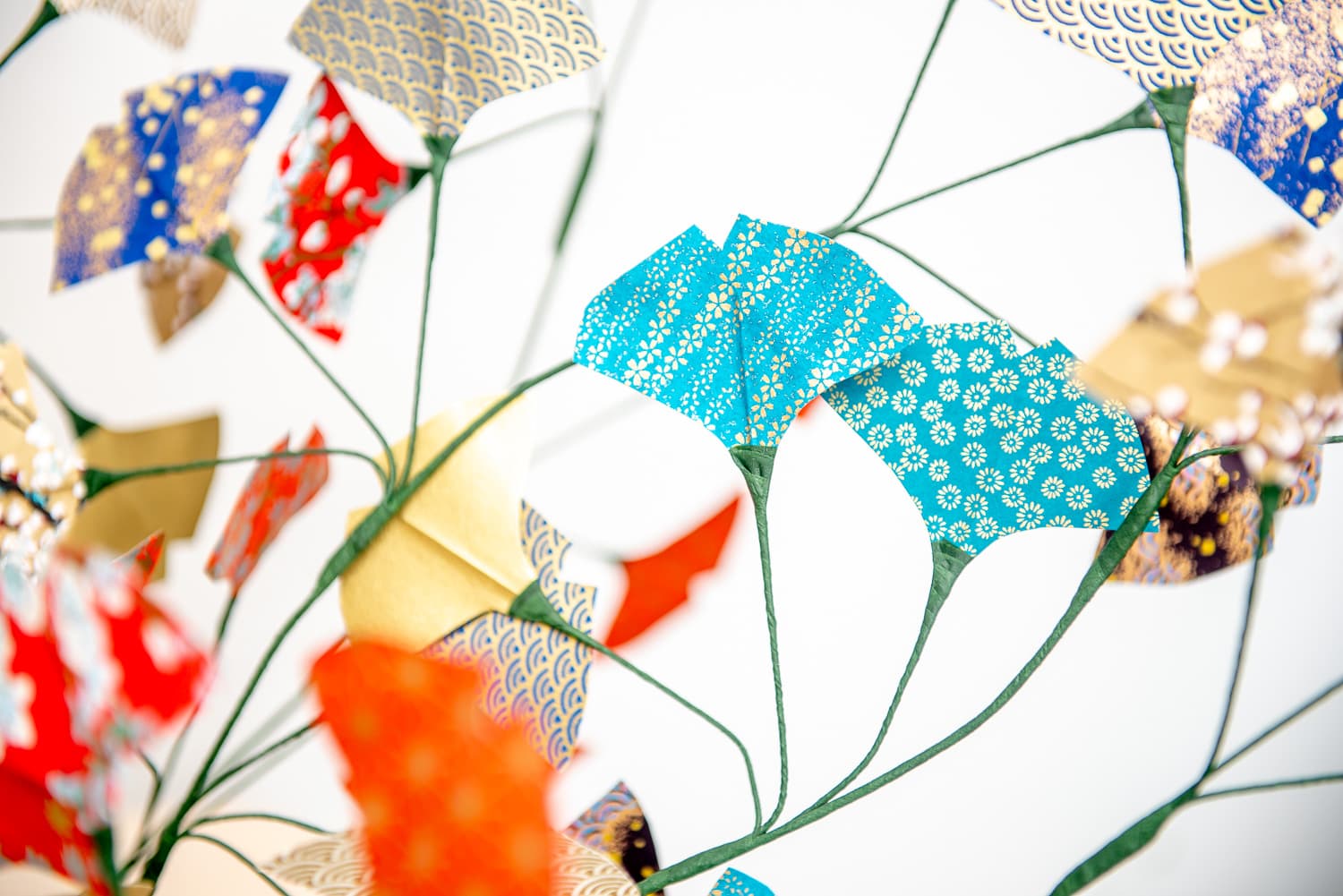 Fleurs en papier washi bleu, rouge et doré, montées sur de fines tiges